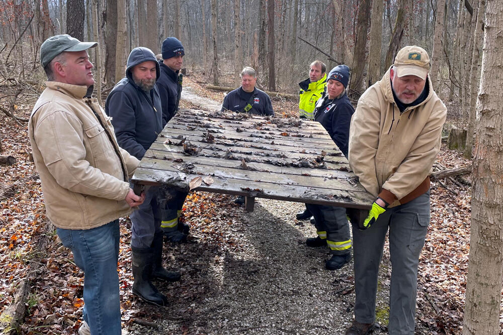Group carrying old bridge in woods